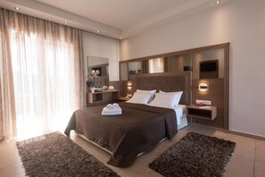 A modern hotel room with a large bed, bedside tables, a mirror, and a view of the outdoors. - Zoe Resort (Pylos-Nestoras)
