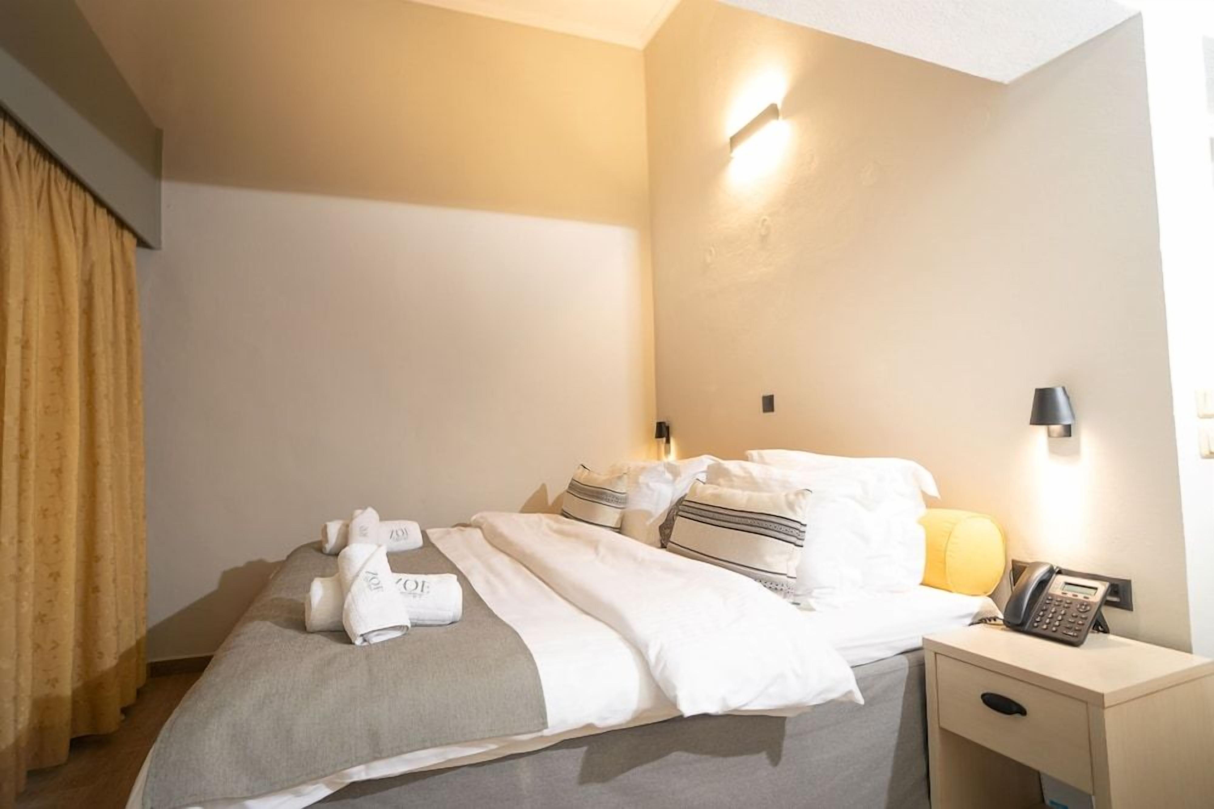 A hotel room with a bed, a bedside table with a lamp, and a telephone.