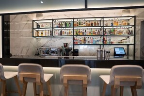 A bar area with multiple shelves of liquor bottles, a coffee machine, and a digital payment terminal. - Zoe Resort (Pylos-Nestoras)