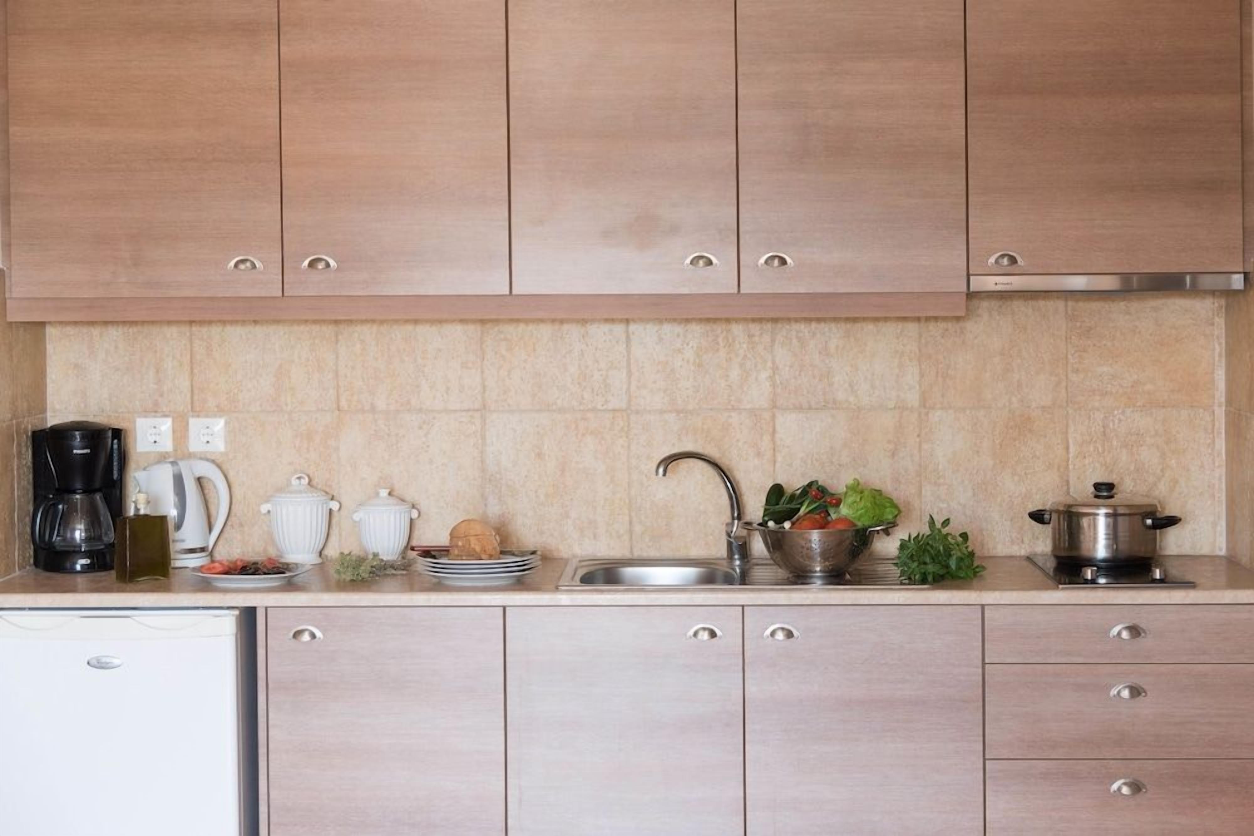 Een keuken met lichte houten kastjes, een RVS spoelbak en diverse keukenapparaten.