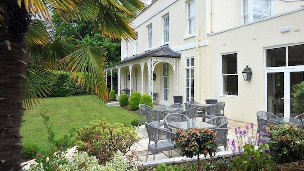 A building with a covered patio area, outdoor seating, and a well-maintained garden.