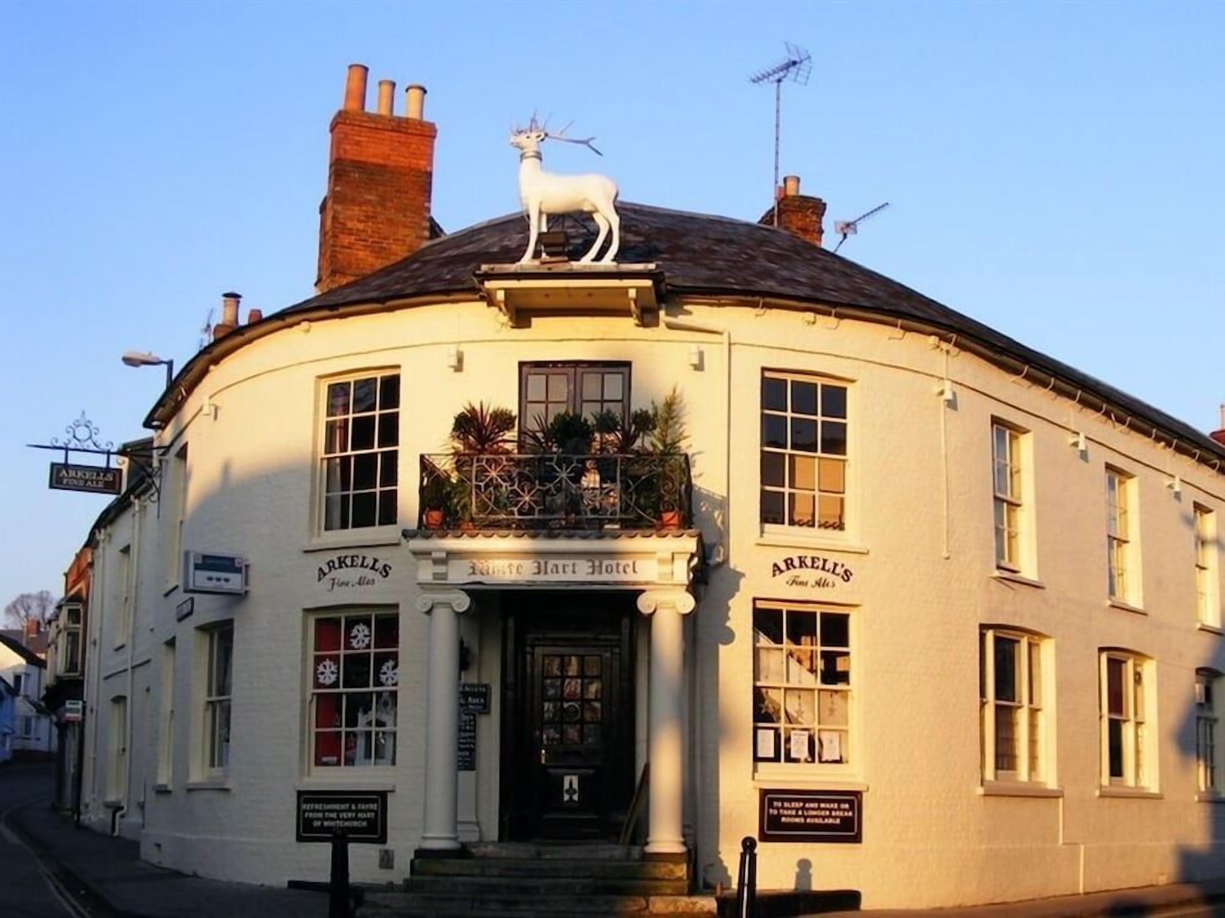 A traditional building with a sign for 'Arkell's' and a horse statue on the roof.