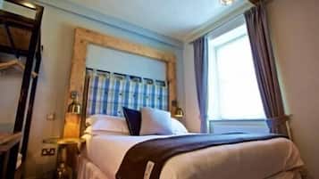 Une chambre d’hôtel avec un lit, des tables de chevet, une lampe et une fenêtre avec des rideaux.