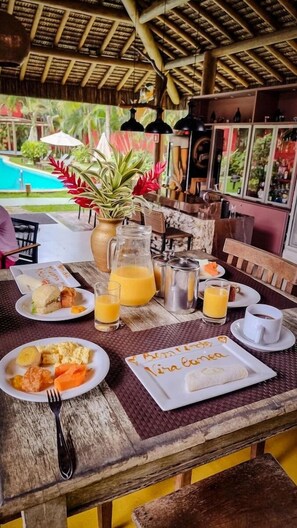 Mesa de café da manhã com pratos de comida, um jarro de suco de laranja e uma xícara de café.