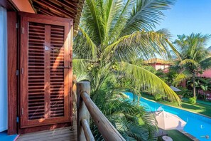 A wooden door with a view of a swimming pool and palm trees. - Vira Canoa (Itacaré)