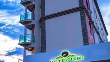 Um hotel com fachada moderna, uma placa de destaque e uma escadaria que leva à entrada.