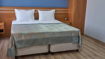 A hotel room with a bed, wooden wardrobe, and a nightstand.