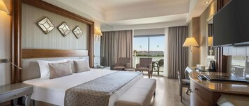 Quarto de hotel com uma cama grande, uma mesa, uma cadeira e vista para o exterior.