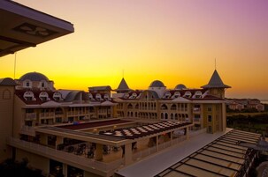 Um hotel com vários andares, um pátio central e vista para o pôr do sol.