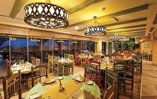 Um restaurante com várias mesas, cadeiras e luminárias pendentes.