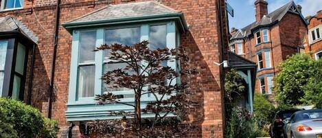 Un bâtiment en briques avec une fenêtre et un petit arbre devant.
