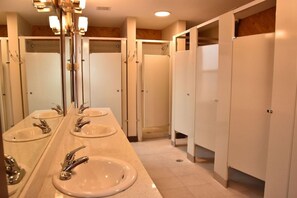 Een badkamer met drie wasbakken, een spiegel en een douchecabine.