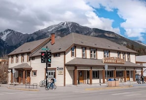 Een hotel met een bord waarop 'CANMORE HOTEL' staat, voor een bergachtige achtergrond.