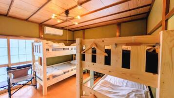 A bunk bed room with a wooden ceiling, a bench, and a window.