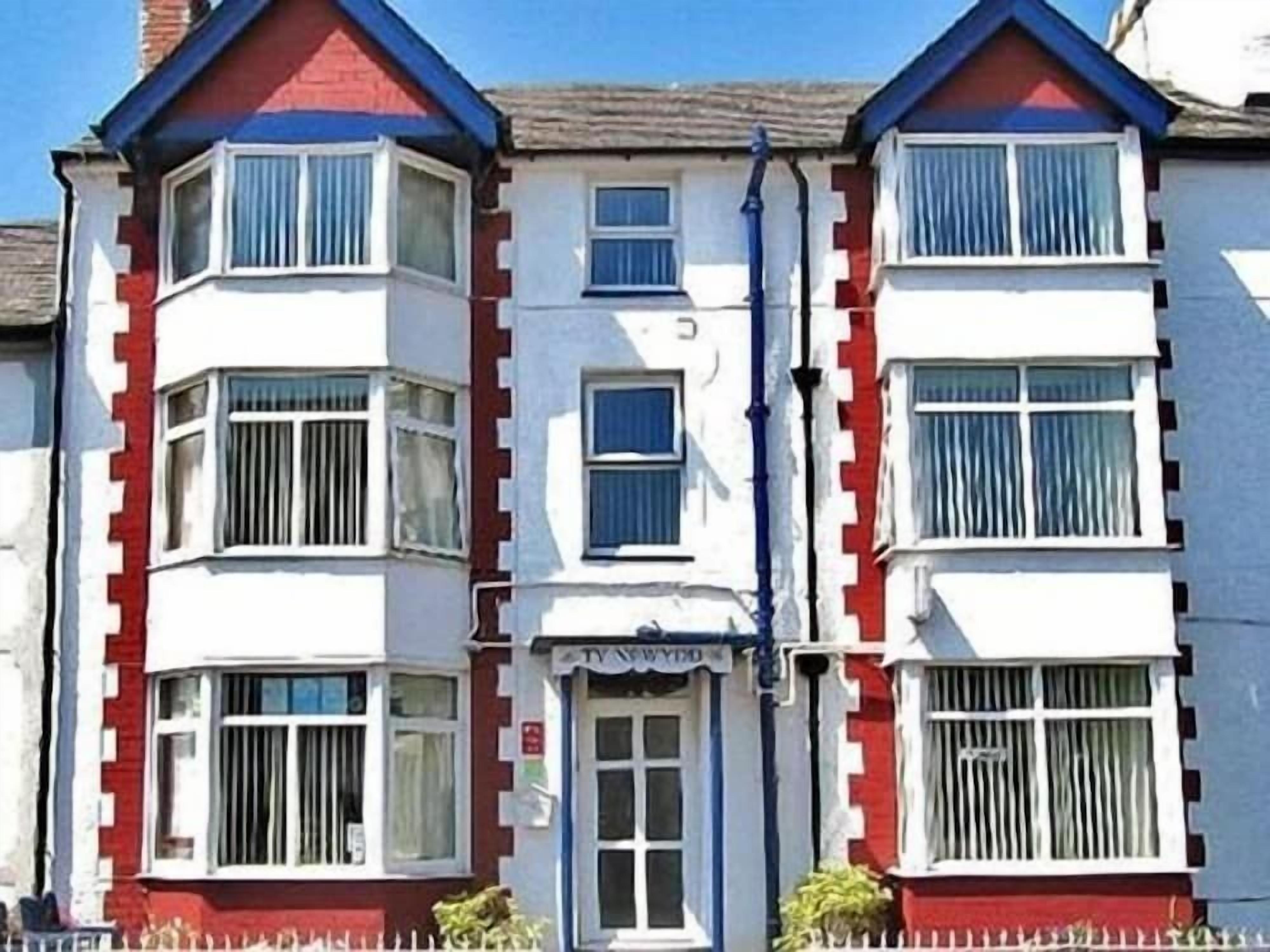 A row of terraced houses with bay windows and a small shop entrance.