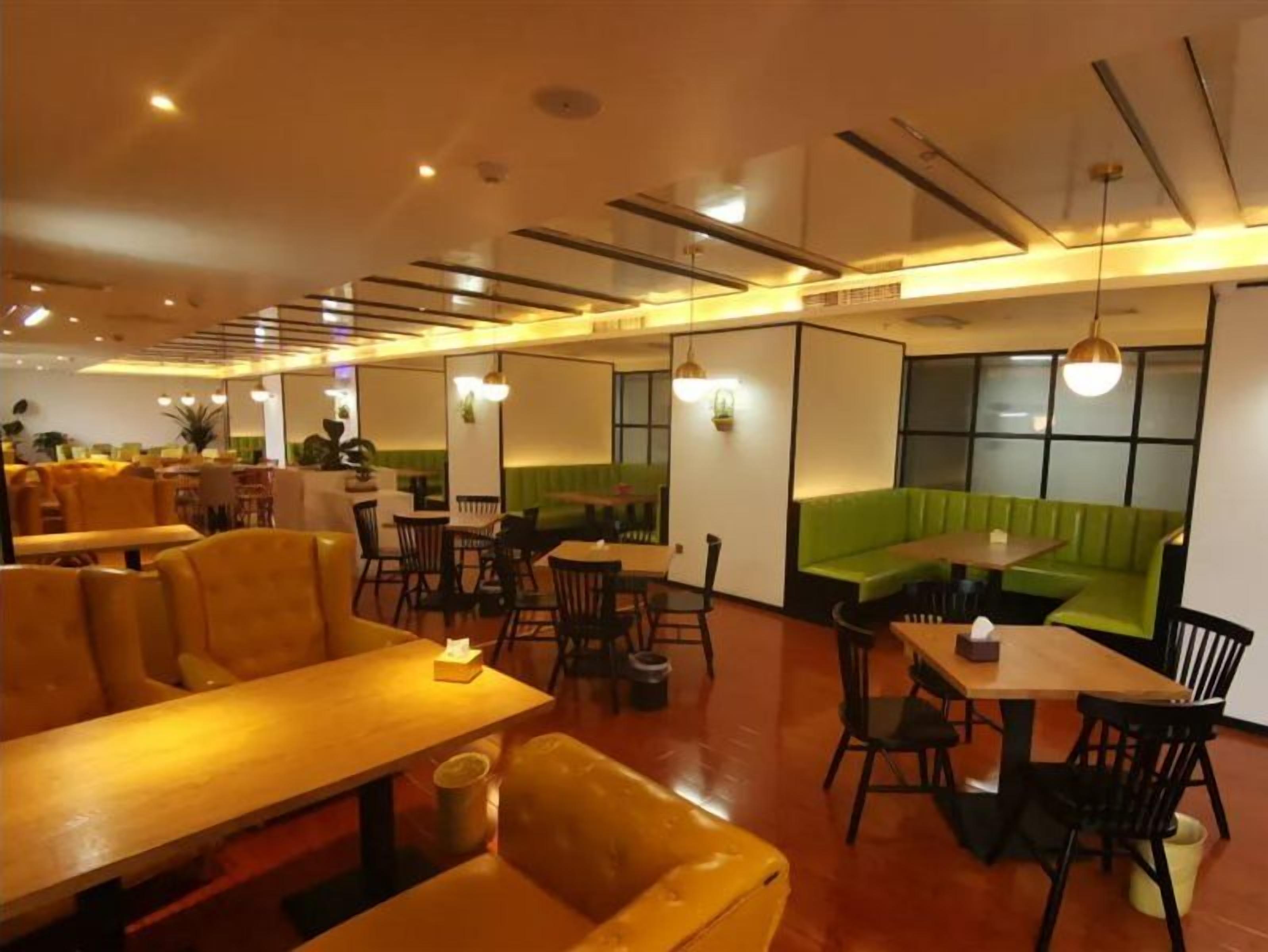 Un restaurante con cabinas, mesas y una zona con sofás verdes.