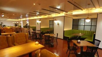 Un restaurante con cabinas, mesas y una zona con sofás verdes.