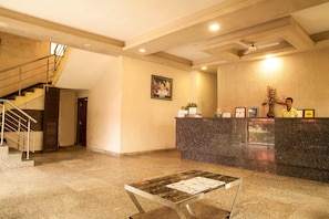 A hotel lobby with a reception desk, a staircase, and a framed portrait on the wall. - The Candlewood Park Beach Resort (Kanthi)