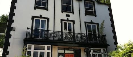 A two-story building with a balcony and a red door.
