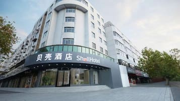 A hotel with a curved facade, large windows, and a sign that reads 'Shell Hotel'.
