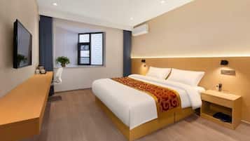 A modern hotel room with a bed, bedside table, and a desk.