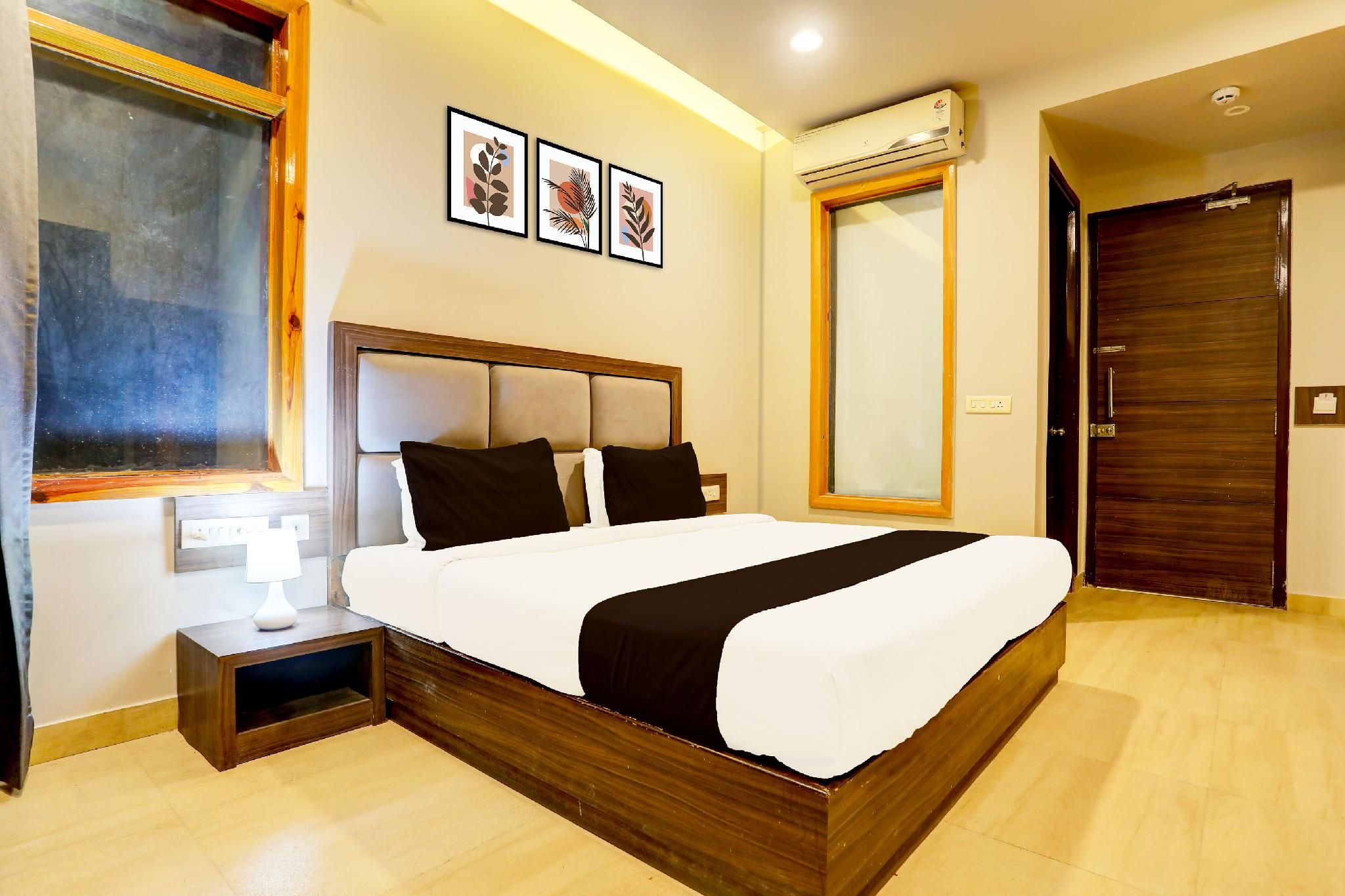 A hotel room with a bed, a nightstand, a bedside table, a window, and a door.