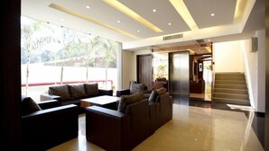 A modern lobby with a seating area, a staircase, and a view of the outdoors. - Hotel Sach Regency (Anand)
