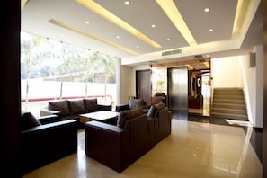 A modern lobby with a seating area, a staircase, and a view of the outdoors. - Hotel Sach Regency (Anand)