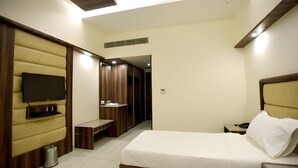 A hotel room with a bed, a TV, a bench, and a wardrobe. - Hotel Sach Regency (Anand)