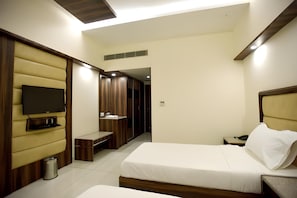 A hotel room with a bed, a TV, a bench, and a wardrobe. - Hotel Sach Regency (Anand)