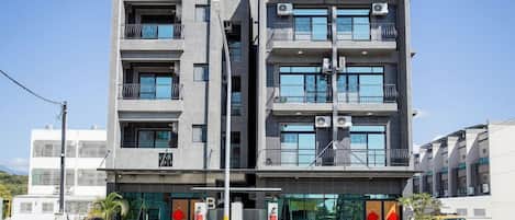 A multi-story building with balconies, air conditioning units, and a gated entrance.
