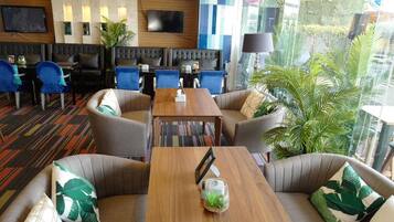 A hotel lobby with a seating area, a television, and a view of the outdoors.