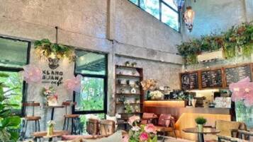 A cafe interior with a high ceiling, wooden tables, chairs, and a counter with a menu board.