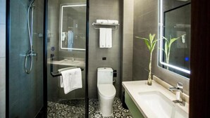 Un baño moderno con ducha de vidrio, inodoro y lavabo con espejo.