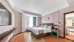 Una habitación de hotel con una cama, mesita de noche, televisor y vista al pasillo.