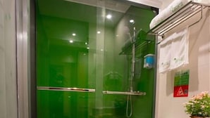 Ein Badezimmer mit Duschkabine, Toilette, Waschbecken und einem Korb mit einem Handtuch.