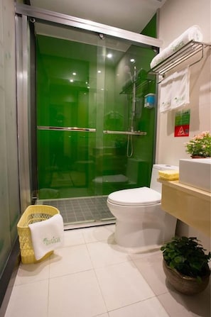 Une salle de bain avec une douche à parois de verre, des toilettes, un lavabo et un panier contenant une serviette.