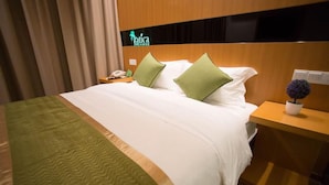 Ein Hotelzimmer mit einem Bett, zwei Kissen, einem Nachttisch, einem Telefon und einem Schild mit dem Namen des Hotels.