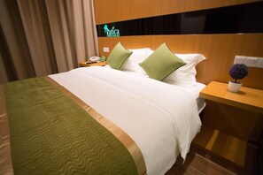 Une chambre d’hôtel comprenant un lit, deux oreillers, une table de chevet, un téléphone et une pancarte indiquant le nom de l’hôtel.