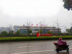 Un edificio moderno con fachada de vidrio y un letrero rojo con caracteres chinos.