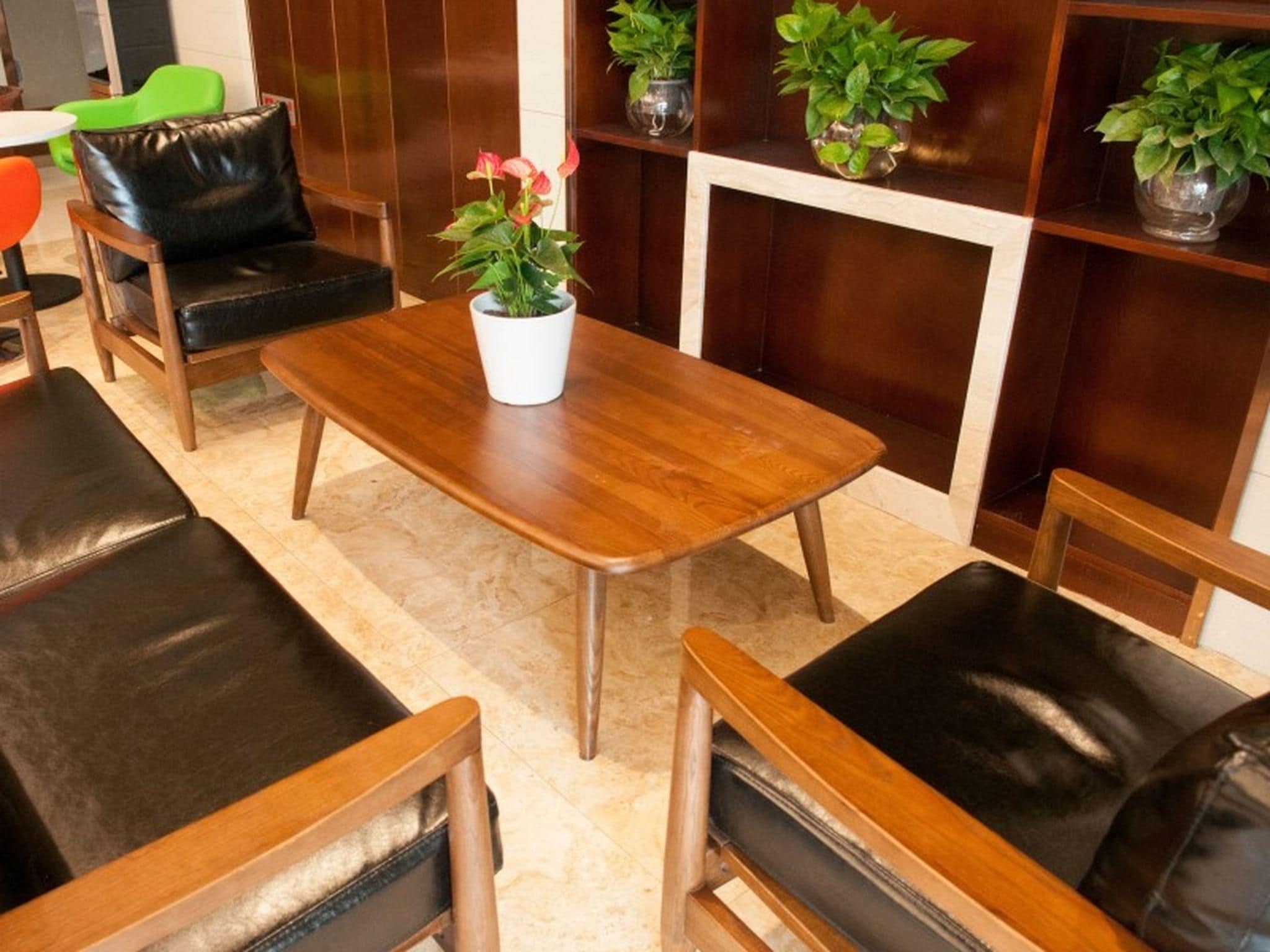 Quarto com mesa de madeira, cadeiras de couro preto e plantas em vasos.