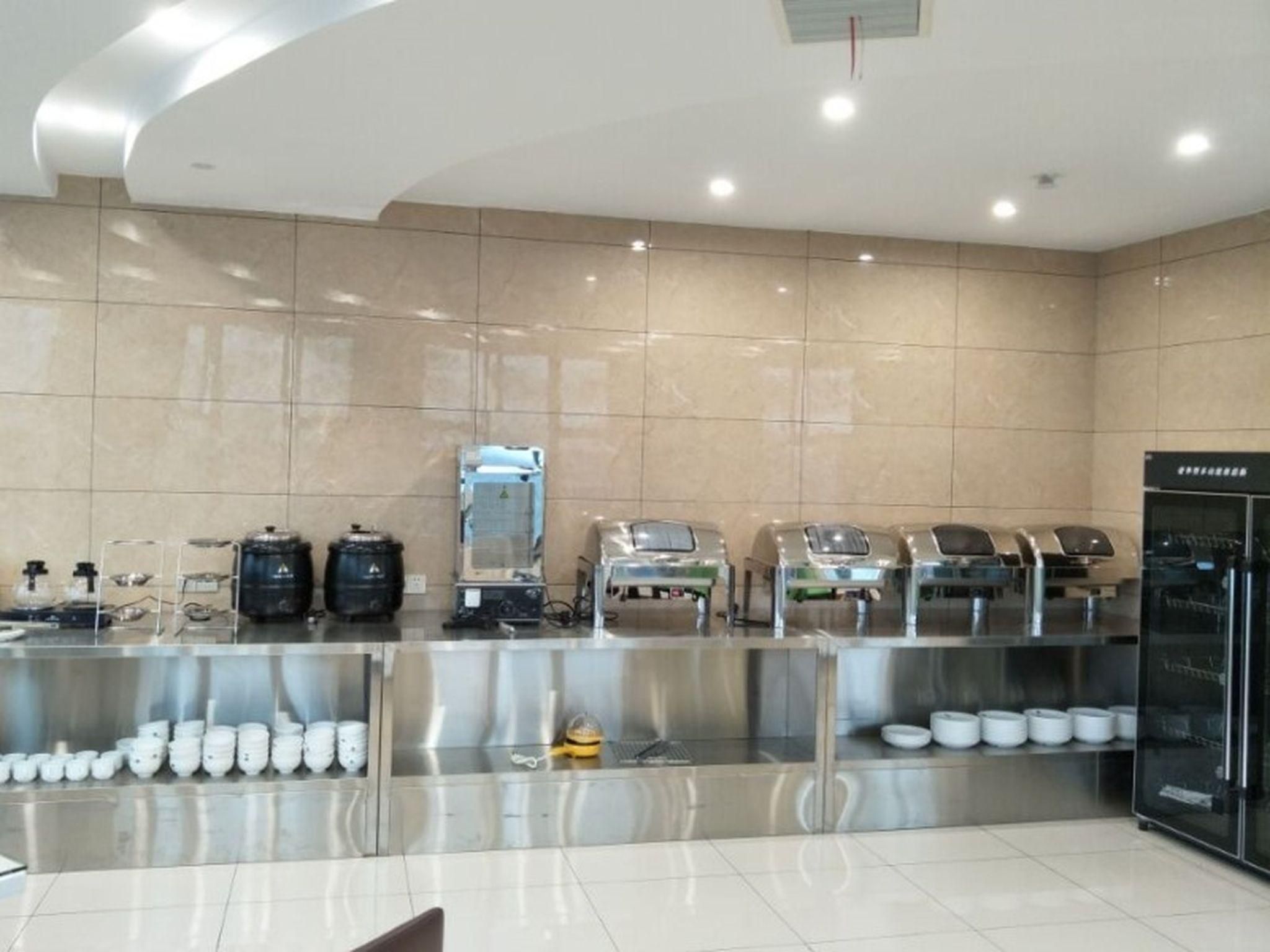 A modern kitchen with stainless steel appliances, a coffee station, and a refrigerator.