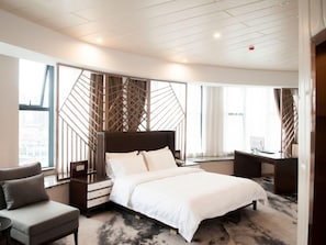 Ein modernes Hotelzimmer mit einem großen Bett, einem Schreibtisch und einem Stuhl.