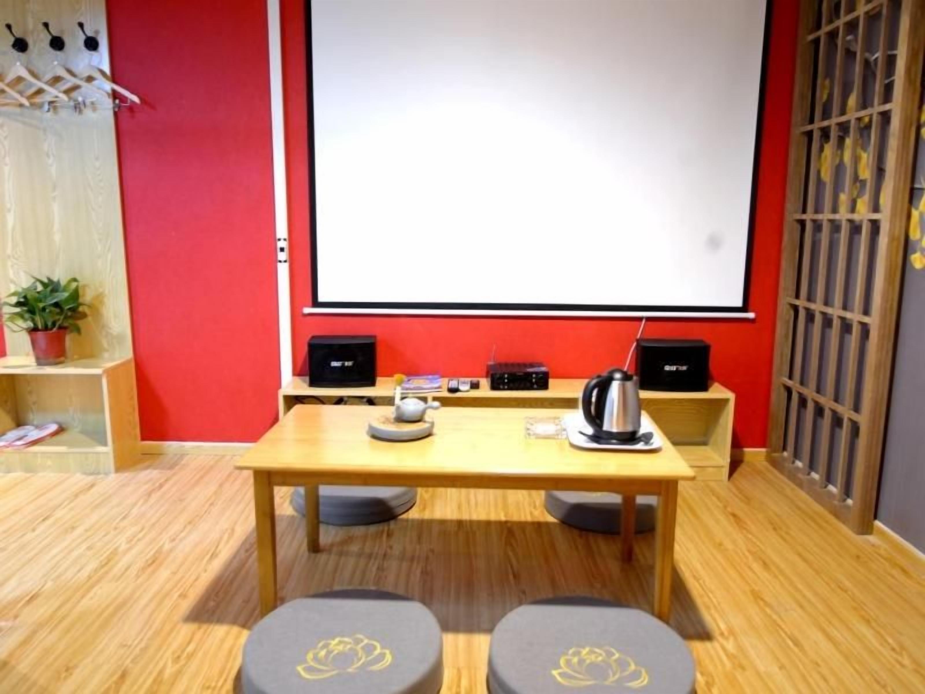 A conference room with a projector screen, a table with a kettle, and two stools.