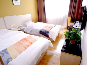 A hotel room with two beds, a desk with a chair, a television, and a potted plant. - Shell Xingtai Railway Station South Xinhua Road Hotel (Xingtai)