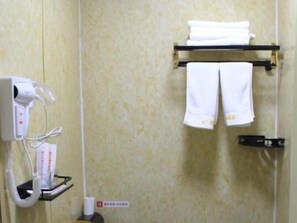 Un baño con un toallero que sostiene dos toallas blancas, un secador de pelo y una botella de champú.