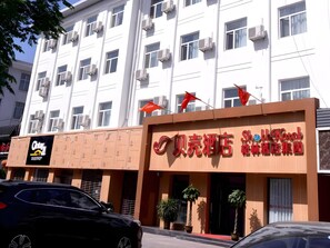 Un hotel con varios pisos, unidades de aire acondicionado y un letrero rojo con caracteres chinos.