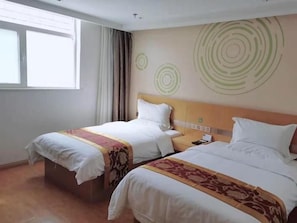 A hotel room with two beds, a window, and a wall with circular patterns.