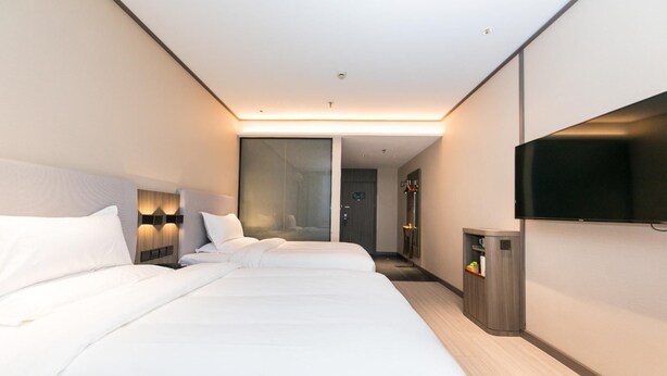 Une chambre d’hôtel avec deux lits, une télévision et un minibar.