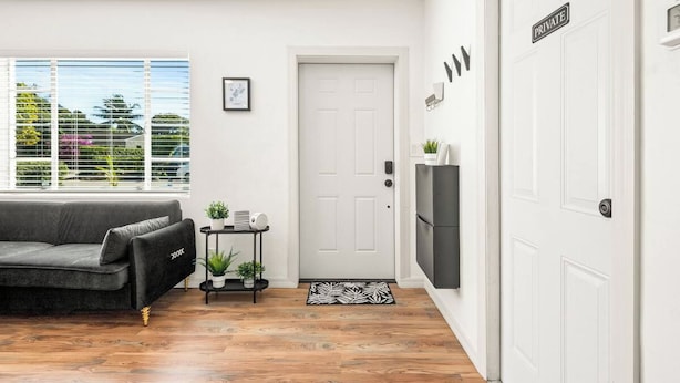 Una sala moderna con un sofá, una mesita con una planta, una puerta con un letrero que dice 'PRIVATE' y vistas a través del ventanal.